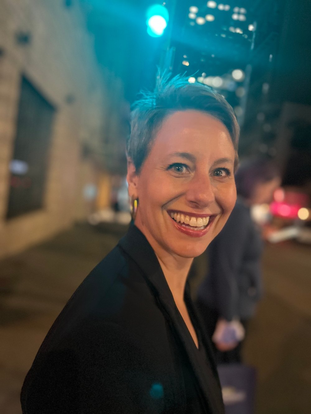Leslie Roulias smiling on a city street at night